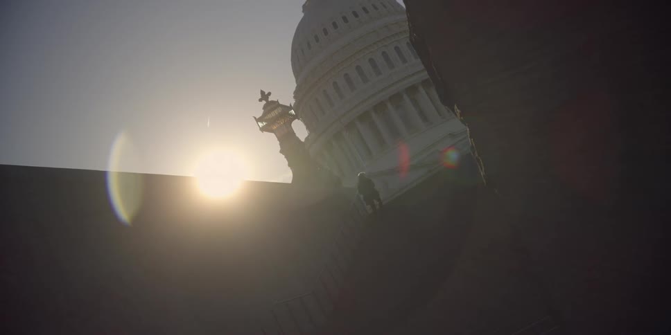A person climbs steps to a capitol building at sunset