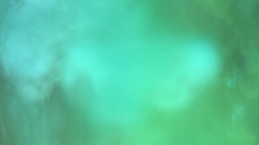 Green and blue bubbles drop through a smoky haze