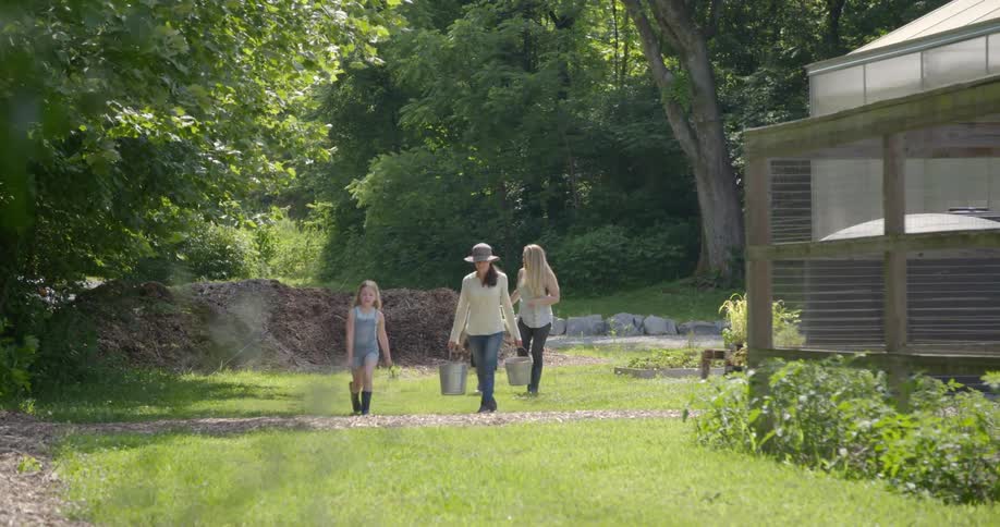 Two women and two children are walking in their garden during the day