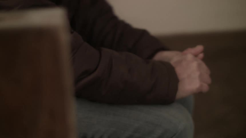Person rubbing his hands together as he sits
