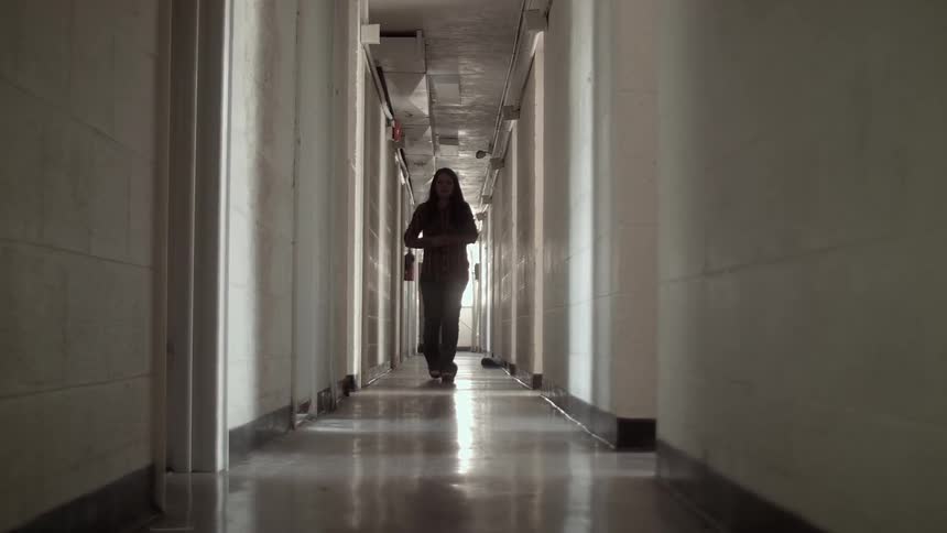 A woman walks down hallway while rubbing her arms