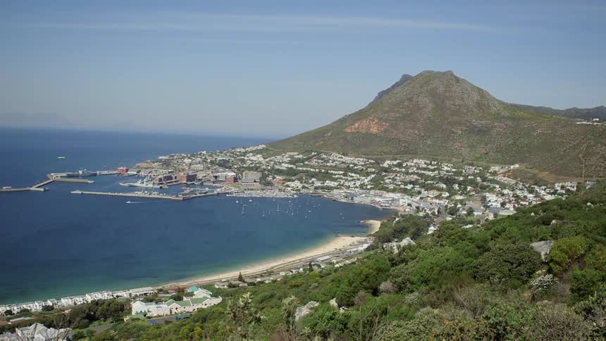 A city sits below a hill and beside water