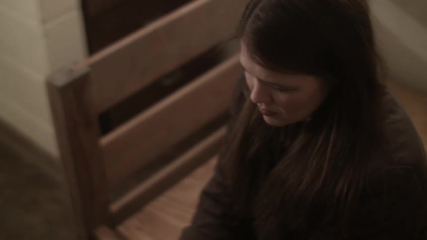 Woman sitting on bench indoors looking very sad