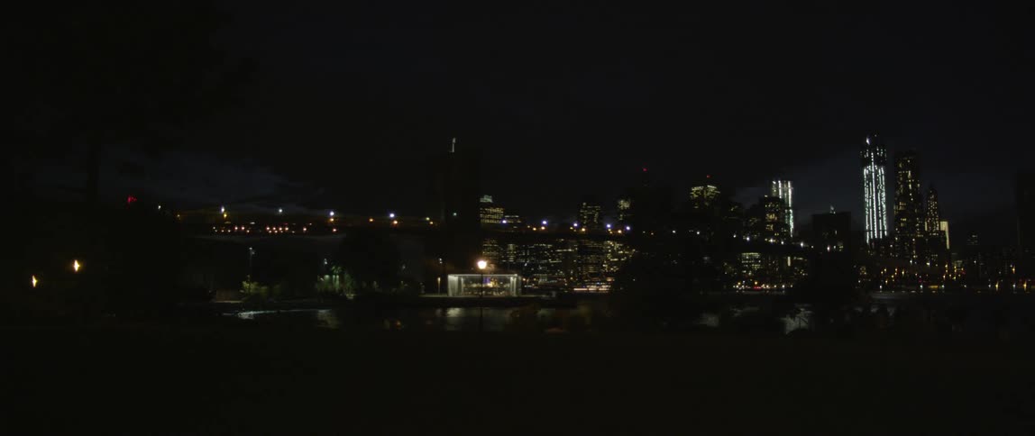 View of a bridge with a brightly lit city behind at night