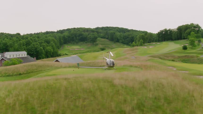 Helicopter sits on a grassy landing pad in a field