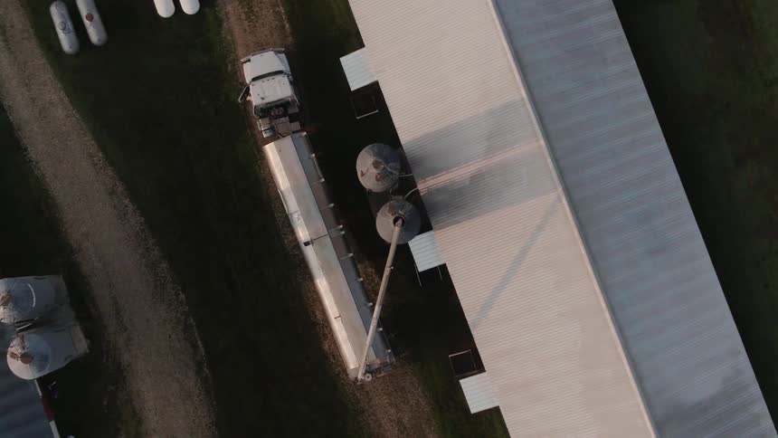 A semi-truck is parked on a farm