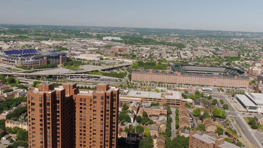 A large city is being flown over with a football stadium in the background