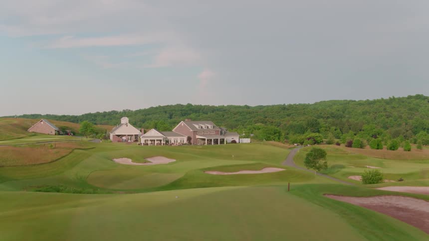 The large golf course has a forest behind it