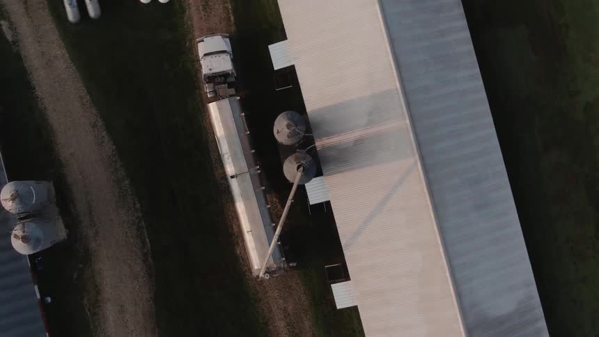 A large truck with trailer is parked near the farm