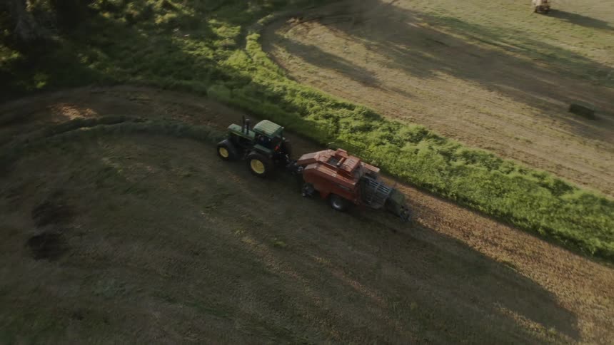 A tractor is traveling around a pasture