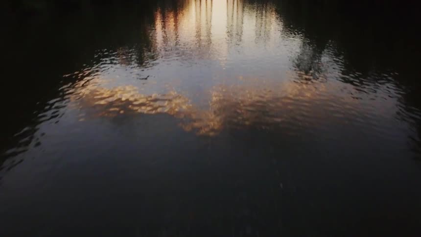 The water is calm underneath this bridge at sunset