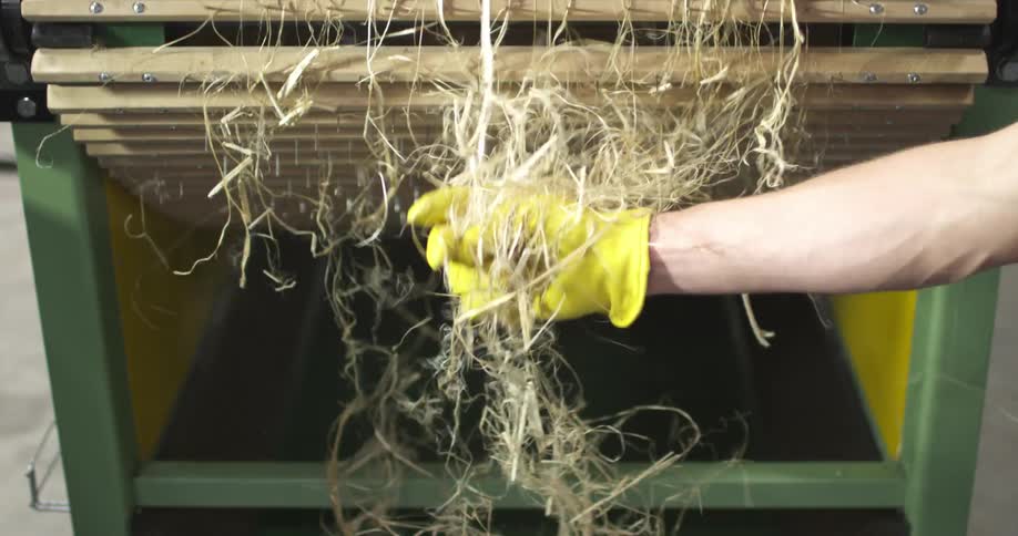 Hay tumbling off a conveyor belt is removed by a hand