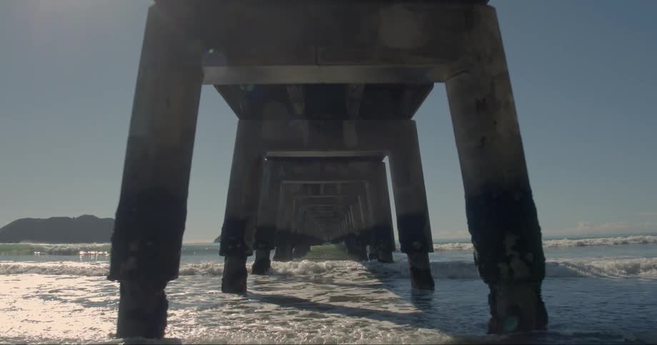Waves are crashing under a pier