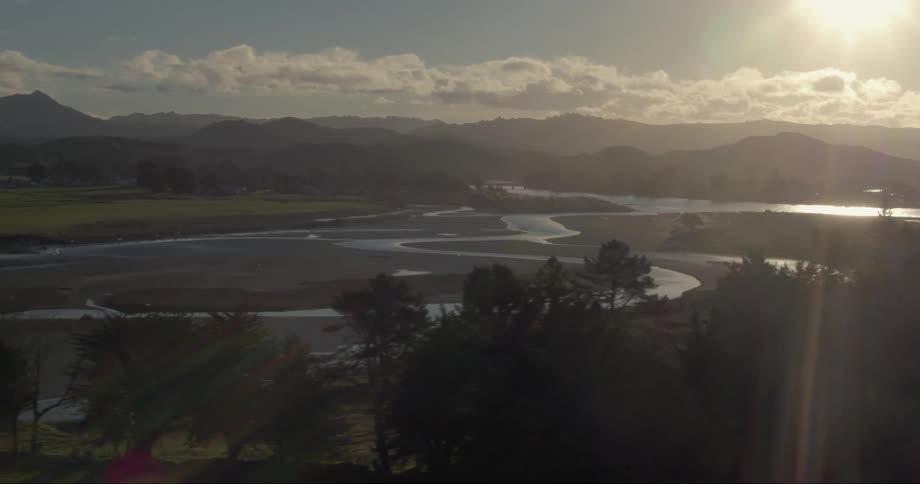The sun shines down on a river and mountains