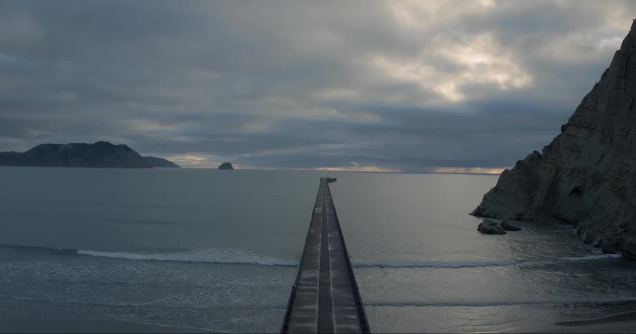 A long wooden pier leads out into the ocean