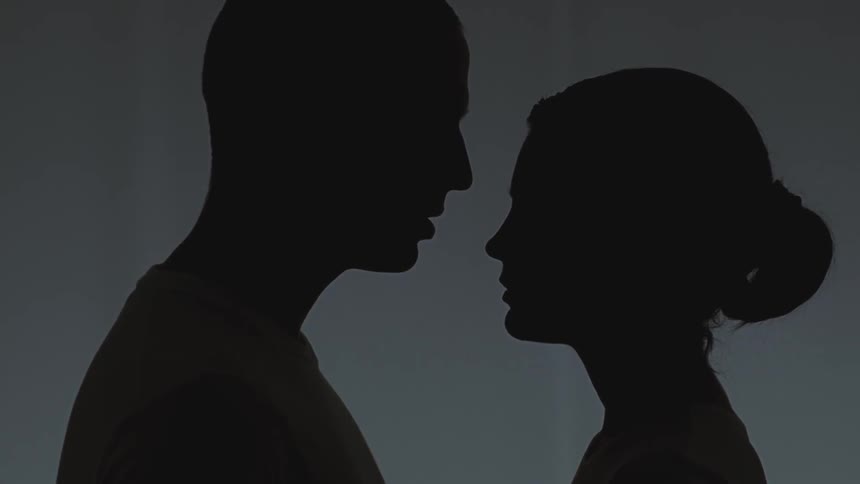 A man and woman move to kiss in the dark