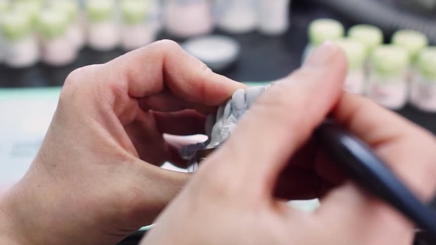 A dentist is painting a tooth of a denture