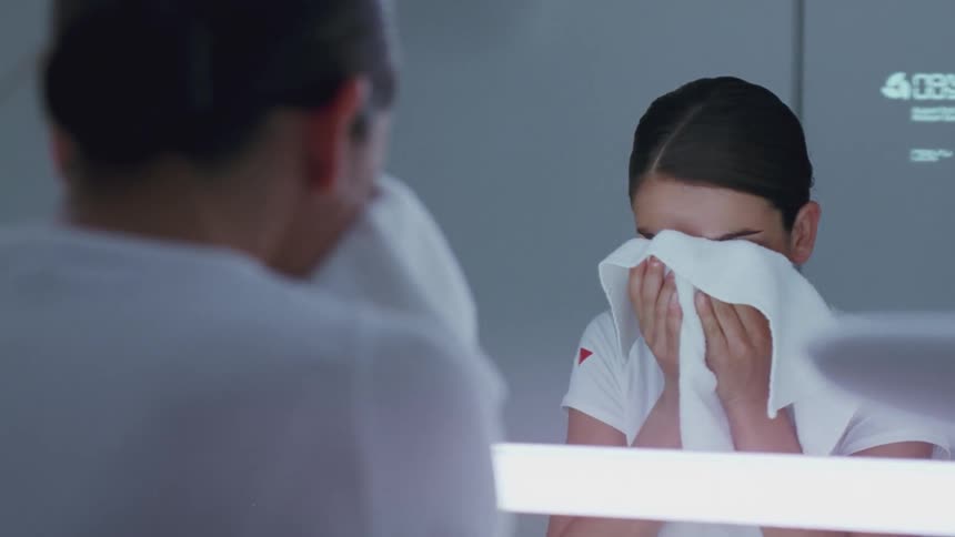 A woman washes her face and dries it with a towel