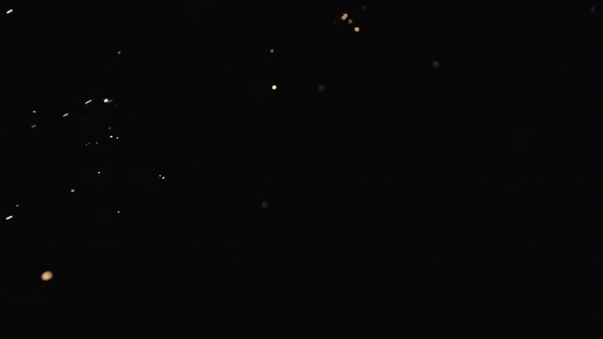 Sparks from a fire are flying across a black screen