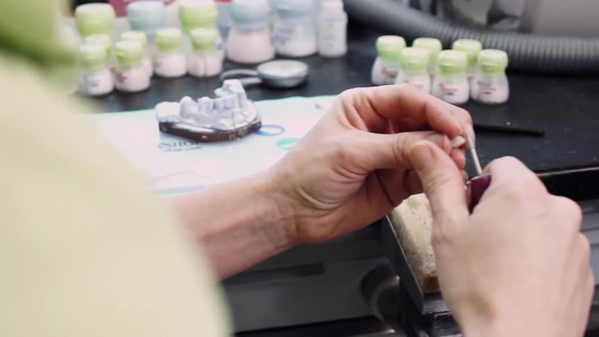 Dentist is carving a tooth for a denture