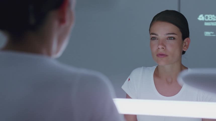 A woman is drying her face with a towel in a futuristic bathroom