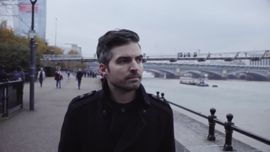 A man is walking alongside the river in a city