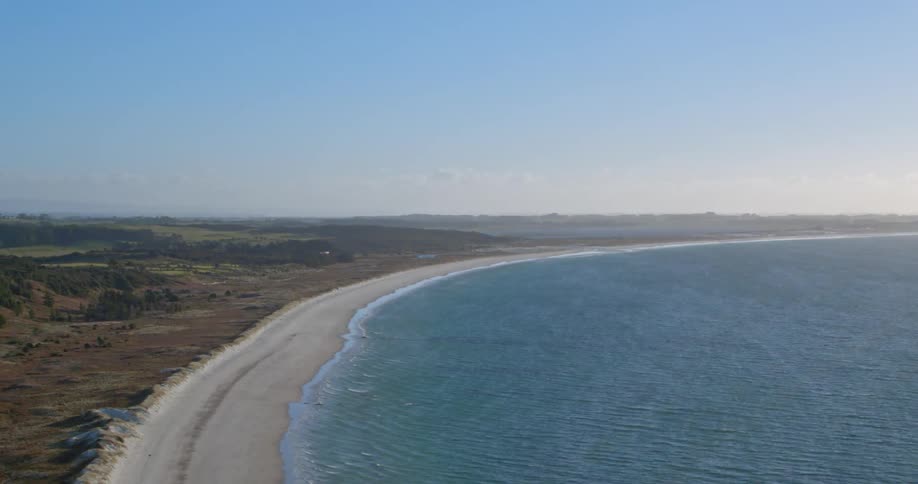 The coast is calm with blue waters slowly hitting the shore
