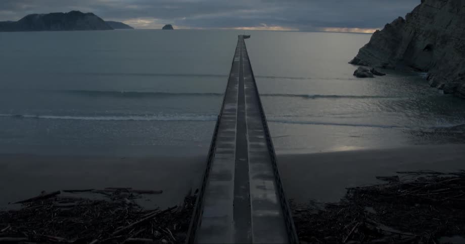 A long wooden pier leads straight to the ocean
