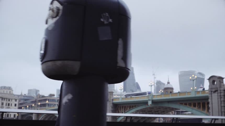 A man walks by a railing with many people sitting in a city