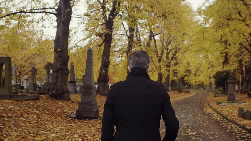 Man walks through a cemetery in the fall