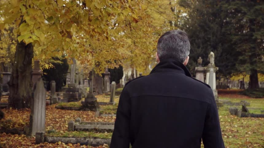 Man walks through cemetery in autumn