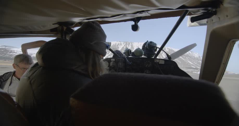 A man is climbing into the cockpit of a propeller plane