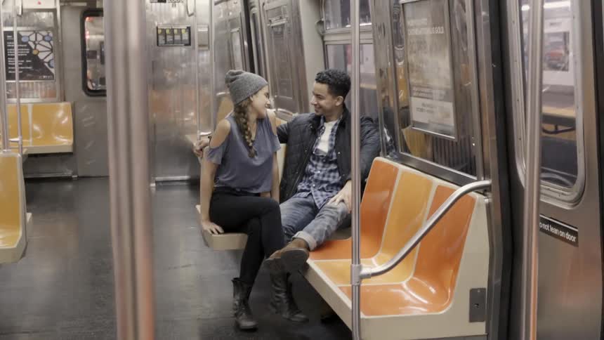 A couple talk on a subway metro seat