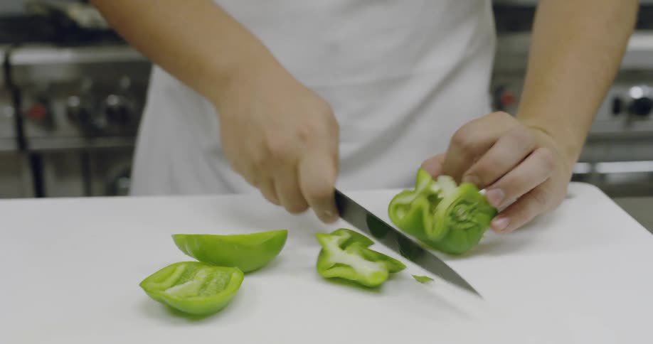 Chef cuts a green bell pepper