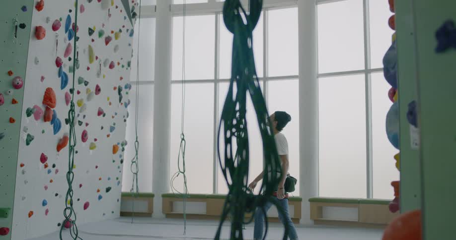A man walks up to a rock climbing wall at a indoor rock climbing gym