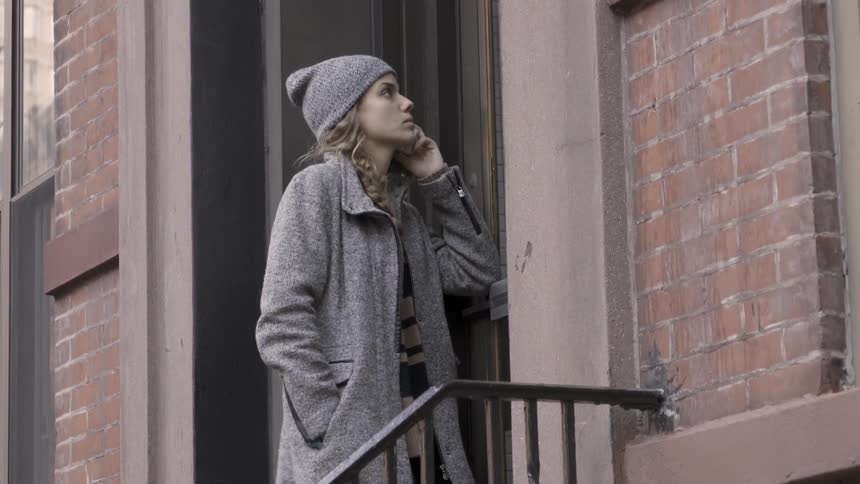 A woman in a beanie calls someone