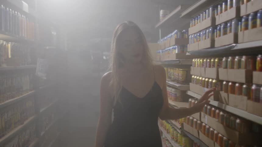 A woman walks down a row of shelved goods