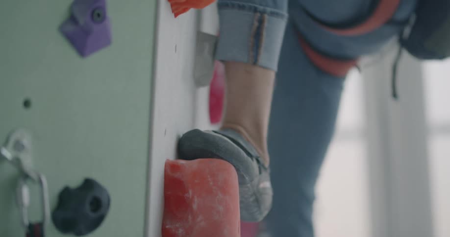 Person climbs up a rock climbing wall