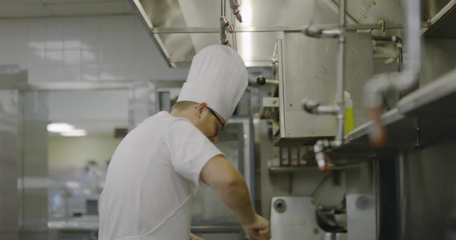 A chef is working in the kitchen walking back and forth