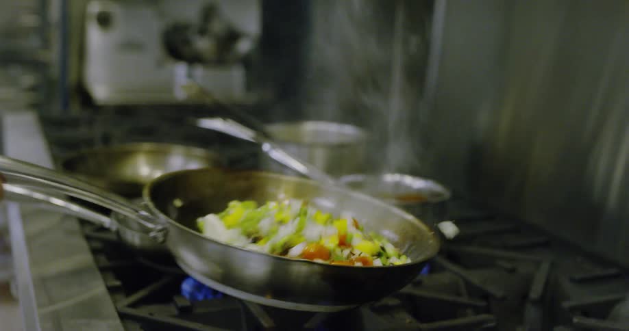 Cook flipping food in a pan over a stovetop