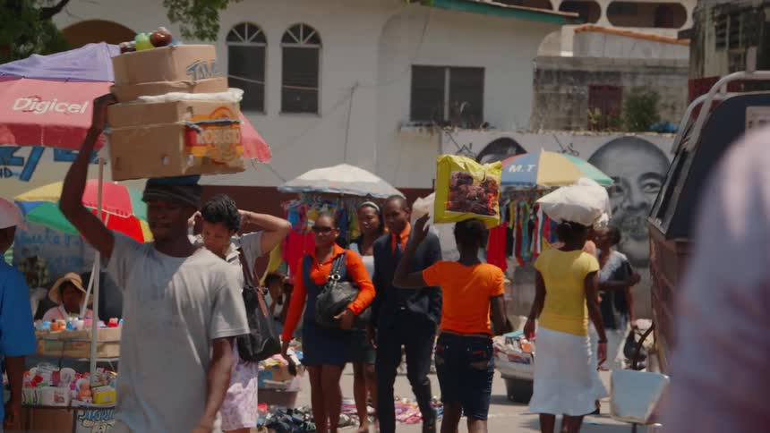 People carry bundles on their heads as they walk through a market in africa