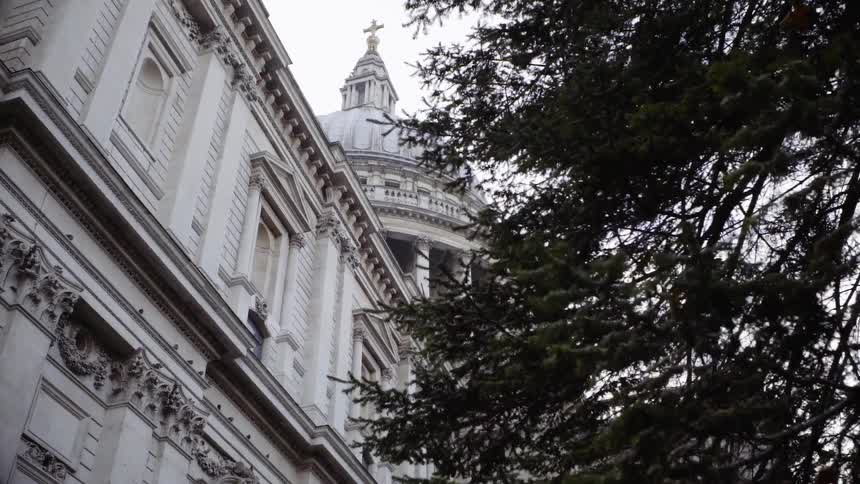 The tall building has a cross at the very top