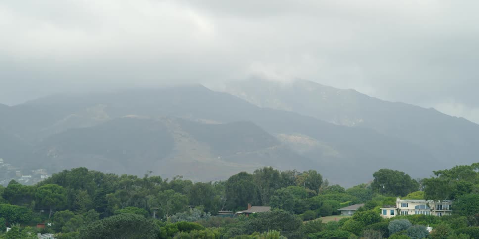 Thick clouds hanging over the top of large mountains