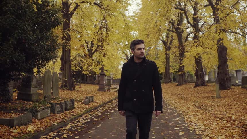 A man walks through a cemetery in autumn