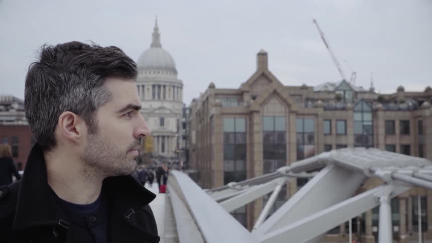 Man stands on a bridge overlooking a city