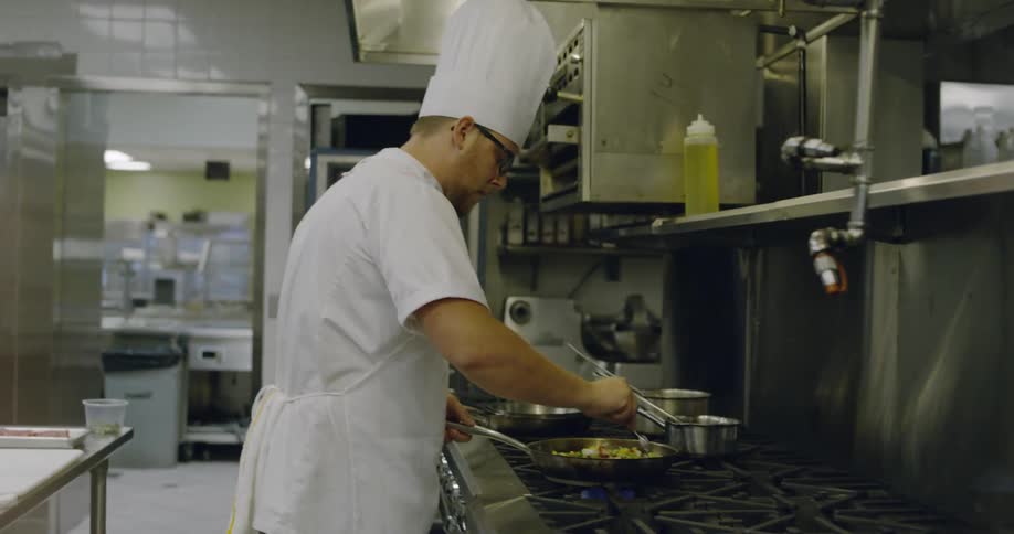 A chef mixes food then flips it in a pan