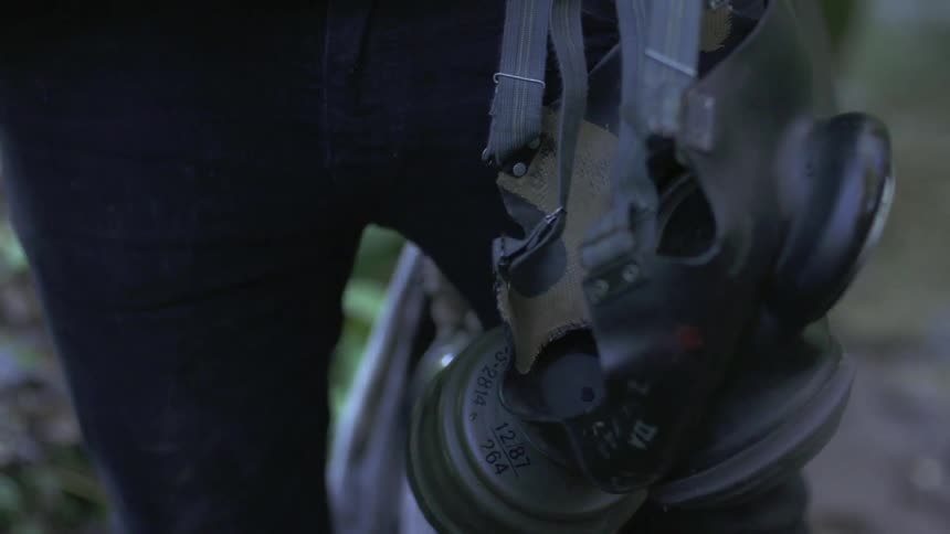 A gas mask is carried by a person