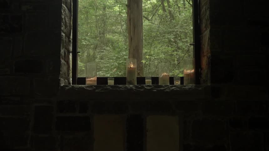 The dark room has candles on the window sill