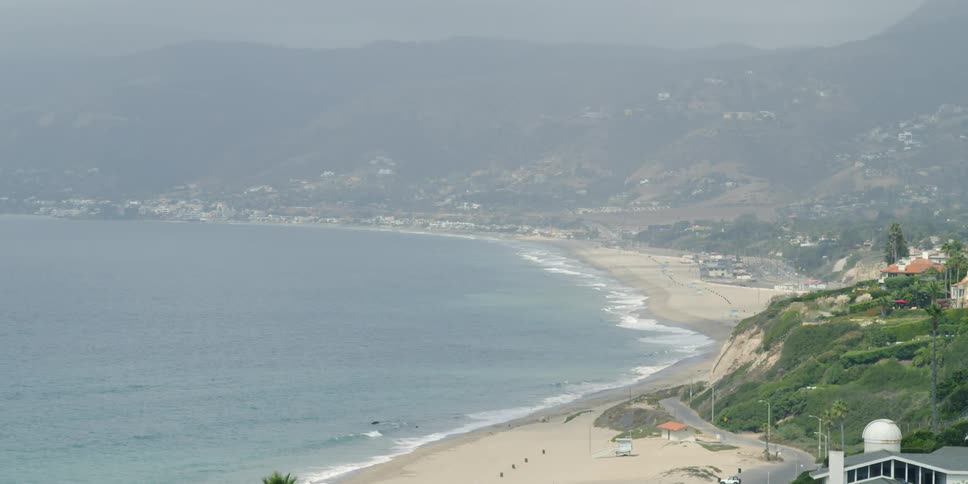 The waves hit the beach of the foggy shore