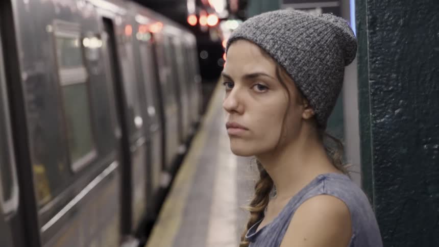 Woman stands at a subway station as the subway leaves